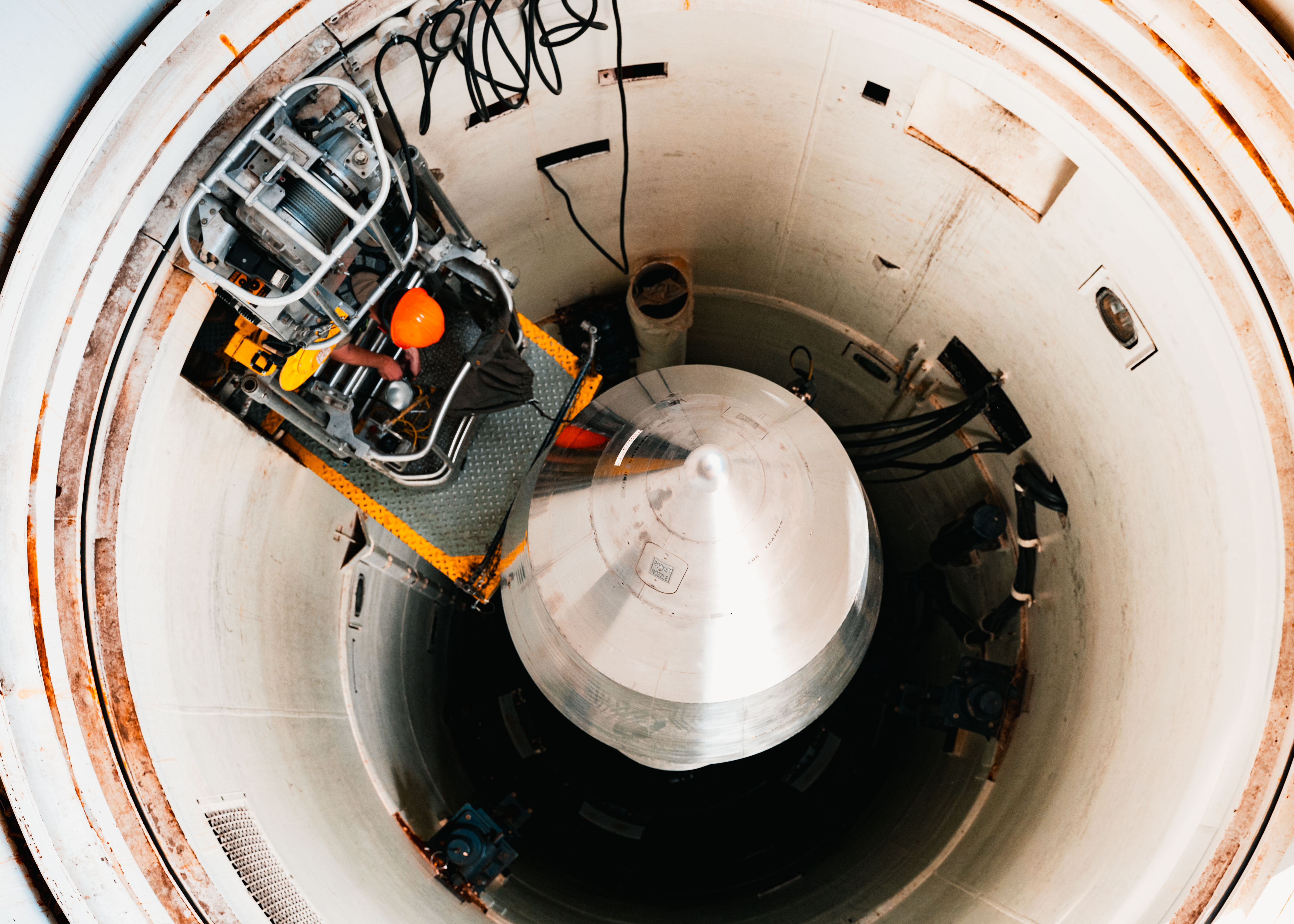 Airman 1st Class Aiden Williams, 90th Missile Maintenance Squadron boardman, climbs onto maintenance platform to enter launch tube during guided missile maintenance platform installation at F.E. Warren Air Force Base, Wyoming, July 9, 2025 (U.S. Air Force/Michael A. Richmond)